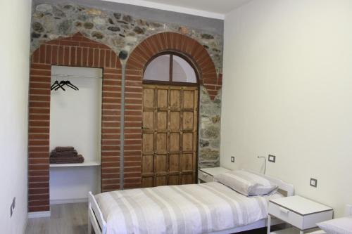 een slaapkamer met een bed en een bakstenen muur bij Passaggio a Nord Ovest in Settimo Vittone