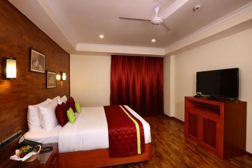 a hotel room with a bed and a flat screen tv at JVK Park Hotel in Cochin