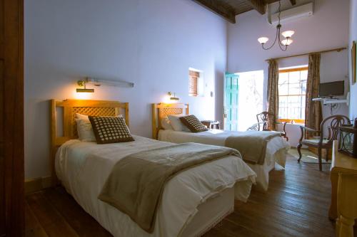 two beds in a room with purple walls and wooden floors at The Barracks in Colesberg