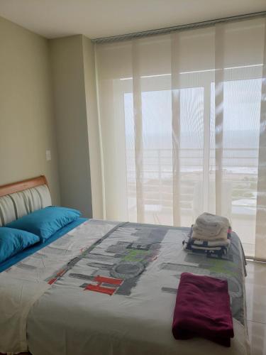 a bedroom with a large bed with a large window at Ocean Club Playas in Playas