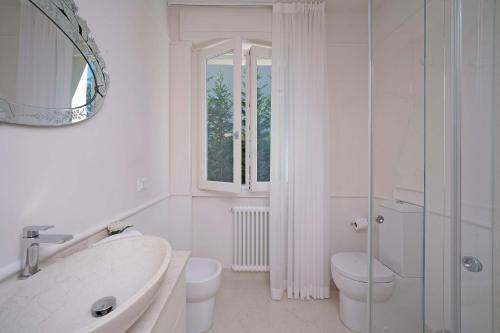 a white bathroom with a toilet and a sink at Villa Sabine: New Modern villa with Private pool in Toscolano Maderno
