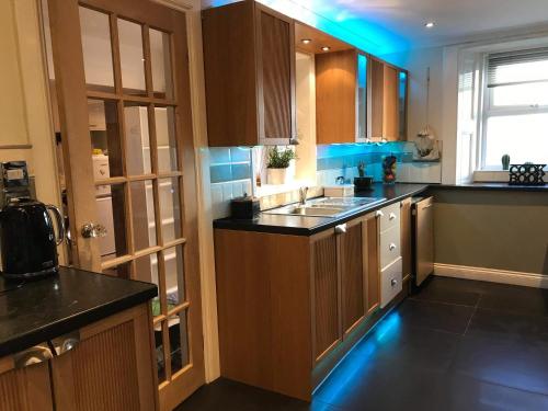 a kitchen with brown cabinets and blue lights in it at Vollie House with Hot Tub, Sauna & Log Burner in Penpont