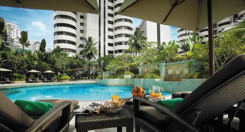 a swimming pool with a table and chairs next to a building at Shangri-La Kuala Lumpur in Kuala Lumpur