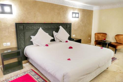a bedroom with a large white bed with red flowers on it at Zalagh Kasbah Hotel & Spa in Marrakech