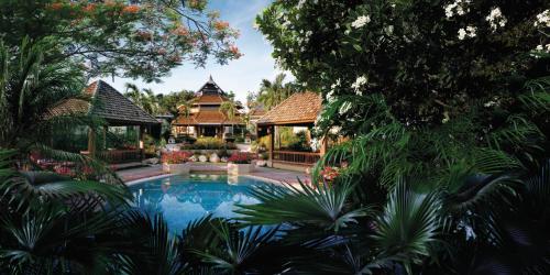 a swimming pool in front of a house with trees at Shangri-La Mactan, Cebu in Mactan