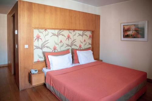 a bedroom with a large bed with a red blanket at Apartamentos Turisticos Atlantida in Funchal
