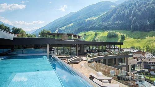 un hotel con piscina y montañas de fondo en LUNARIS Wellnessresort, en Cadipietra