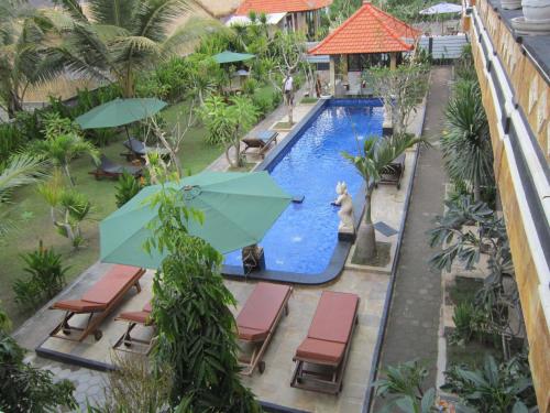 an overhead view of a swimming pool with chairs and umbrellas at Nitya Home Stay Lembongan in Nusa Lembongan
