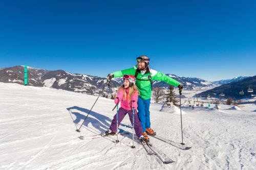 a man and a girl on skis in the snow at Grand Hotel Zell am See in Zell am See
