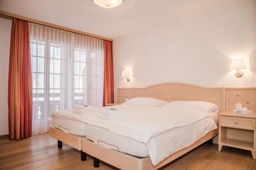 a bedroom with a large white bed and a window at Apartment Stotzhalten 3.5 - GriwaRent AG in Grindelwald