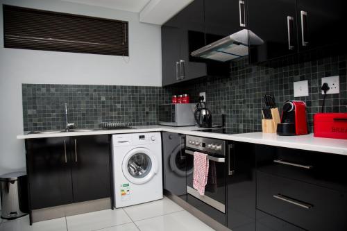 a kitchen with black cabinets and a washer and dryer at Apartment 27 in Windhoek