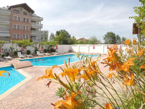 een zwembad in een hotel met oranje bloemen bij Alba Family Club Hotel in Primorsko