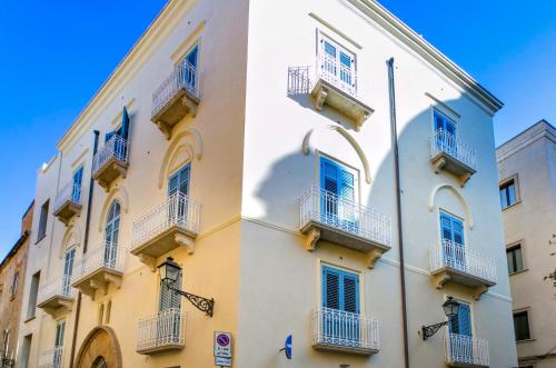 a white building with blue windows and balconies at ZIBIBBO SUITES & ROOMS - Aparthotel in Centro Storico a Trapani in Trapani