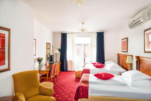 una habitación de hotel con 2 camas y una silla en Hotel Leon D´Oro en Praga