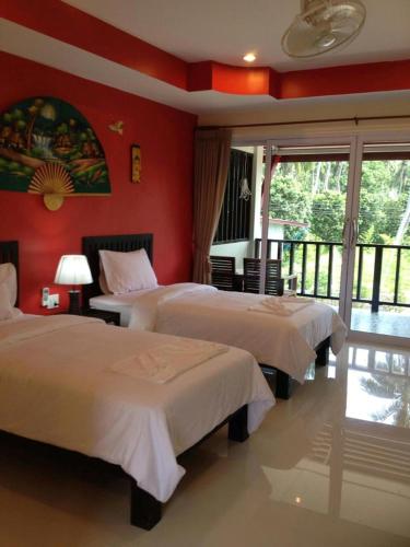 two beds in a room with red walls at Nadapa Resort in Ko Tao