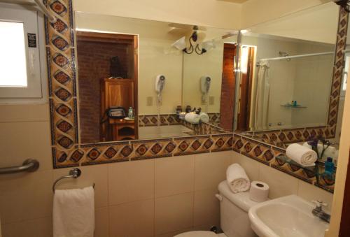 a bathroom with a toilet and a sink and a mirror at Hotel Vieja Cuba in Quito