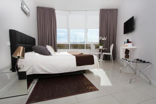 a bedroom with a bed and a large window at Bleu Mer Duplex & Suites in Saint-Cyprien