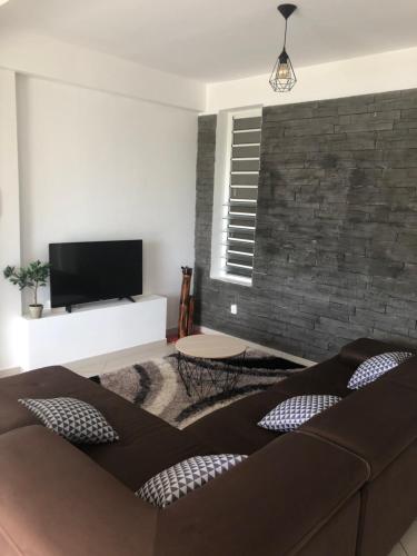 a living room with a couch and a flat screen tv at Appartement « Lilas » SEAVIEW in Le Marin