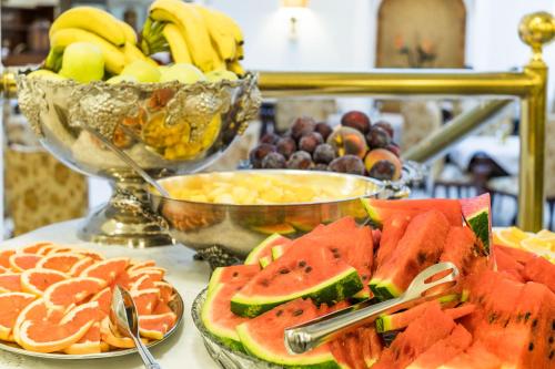 a table topped with plates of fruit and a bowl of bananas at Hotel Leon D´Oro in Prague