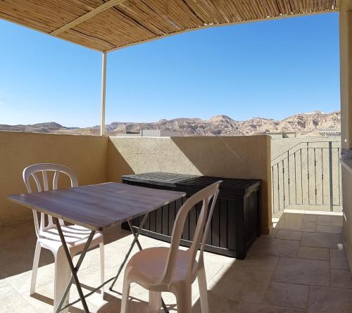 a table and chairs on a balcony with a view of the desert at The Birdwatchers Nest in Beʼer Ora