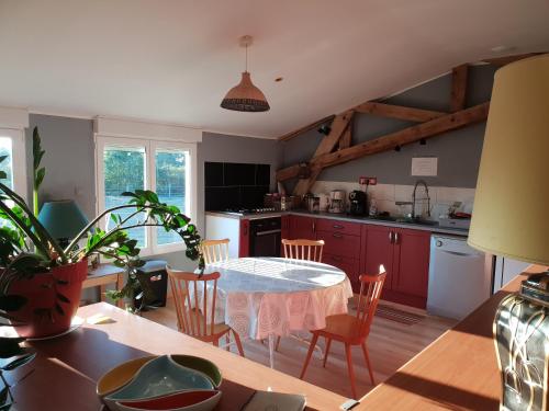 une cuisine avec des placards rouges et une table avec des chaises dans l'établissement Chambre d'hôte de l'élevage du Lattay, à Châteauneuf-sur-Sarthe