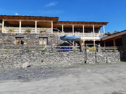 a building with a stone wall and a balcony at Guesthouse Lasharai in Omalo