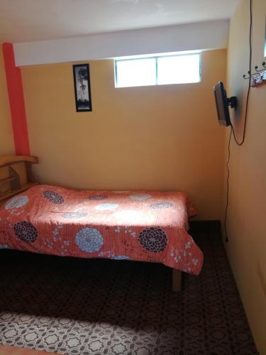 a bedroom with a bed with a red bedspread and a window at Hostal Puerto Alegre in Copacabana