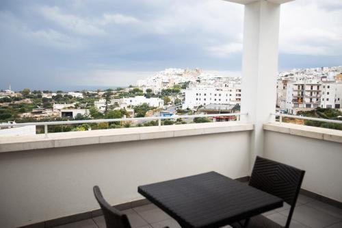 a dining room table with a balcony overlooking a city at Hotel Monte Sarago in Ostuni