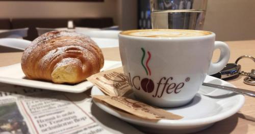 uma chávena de café e um bolo numa mesa em Hotel Marta em Forlì