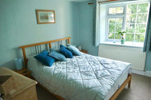 a bedroom with a bed with blue pillows on it at Ivy Cottage in Stawell