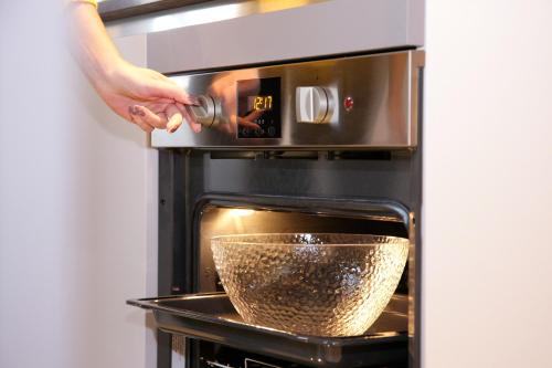 a person is putting a bowl in an oven at Aparthotel Zell am See (Contactless Check-In) in Zell am See