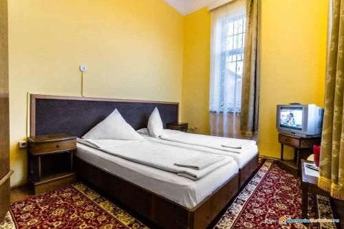 een slaapkamer met een groot bed en een televisie bij Pensiunea Onix in Făgăraş