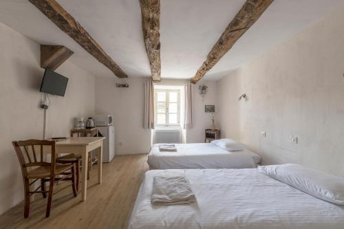 Un dormitorio con dos camas y una mesa y un escritorio. en La maison d'Angèle, en Sainte-Eulalie-du-Cernon