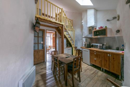 cocina con mesa de madera y escalera de madera en La maison d'Angèle en Sainte-Eulalie-du-Cernon