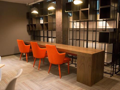 a conference room with a wooden table and orange chairs at Hotel Fenix in Guadalajara