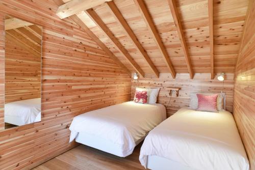 two beds in a room with wooden walls at Porto Pim Bay in Horta