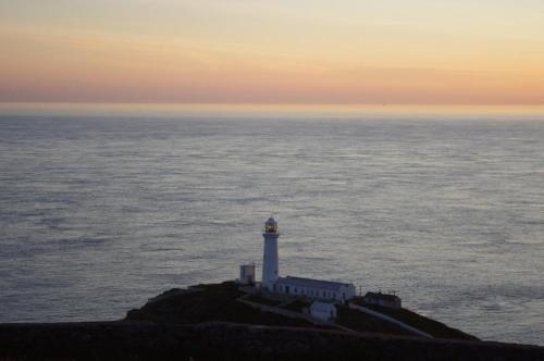 a lighthouse on a small island in the ocean at Cae Glas Apartments in Holyhead