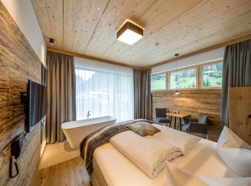 een slaapkamer met een bed, een bureau en een televisie bij Post Hotel Paznaun in See