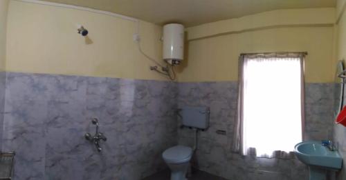 a bathroom with a toilet and a sink and a window at Goshen homestay in Cherrapunji