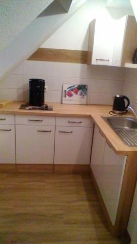 a kitchen with white cabinets and a sink at Ferienwohnung Rosenflair in Schönebeck