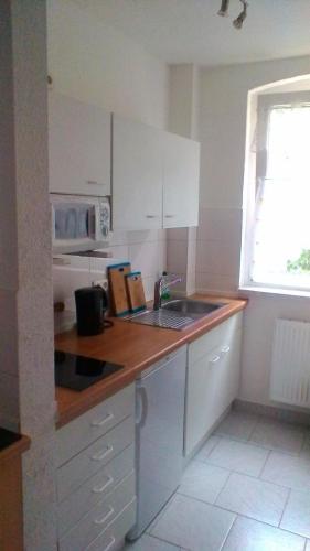 a kitchen with white cabinets and a sink and a window at Ferienwohnung Rosenflair in Schönebeck