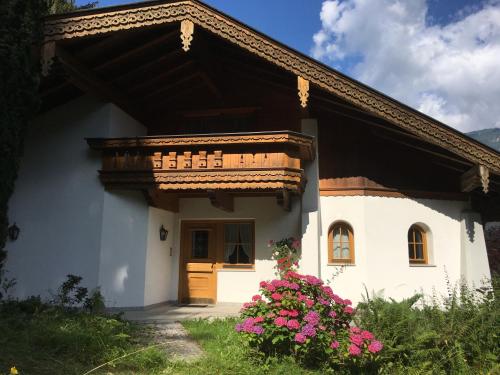 a white house with a wooden door and flowers at Ferienwohnung Bacher Oberkumbichl 900 in Mayrhofen