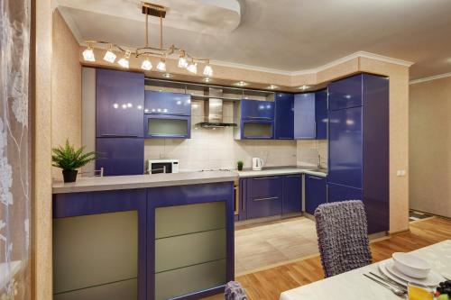 カザンにあるTihomirnova apartmentsの青いキャビネットとテーブル付きの広いキッチン