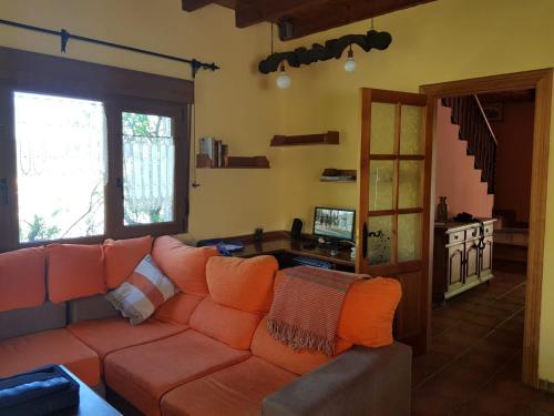 un soggiorno con divano arancione e TV di Casa Rural El Hórreo a Santa Maria de Valdeón