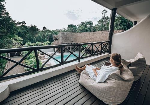 
a person laying on a balcony looking out over the water at Xcacel Dreams in Chemuyil
