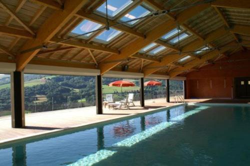 - une piscine dans une maison avec un parasol dans l'établissement Madame Vacances - Résidence La Marquisié, à Trébas