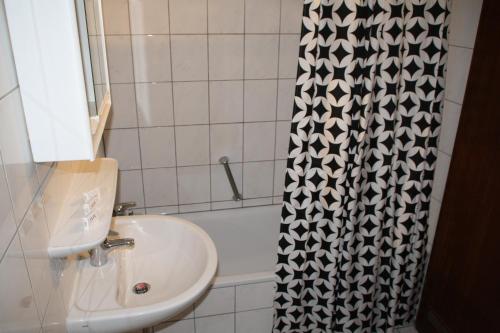ein Bad mit einem Waschbecken und einem Duschvorhang in der Unterkunft Hotel Restaurant Balkan in Trier