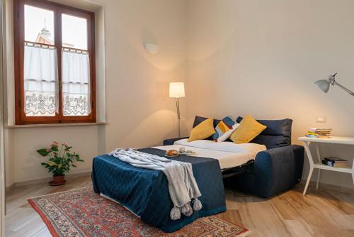 a bedroom with a bed and a couch and a window at Minerva Apartment in Casciana Terme