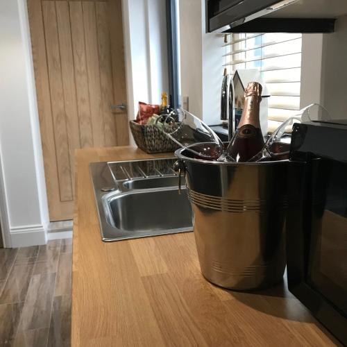a bucket with a bottle of wine in it next to a sink at Daisy House Filey in Filey