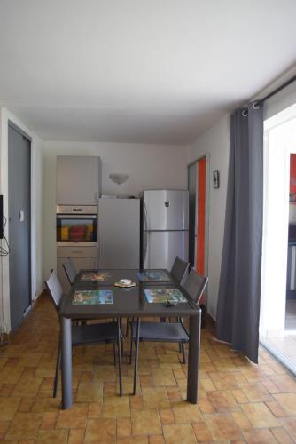 a dining room with a table and a refrigerator at Le Paradis des Doudous/Résidence Corail in Sainte-Anne